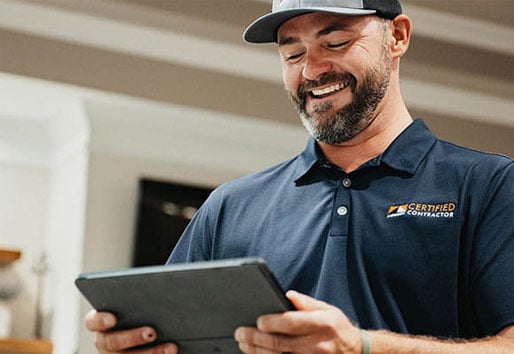 Andersen Certified Contractor smiling while looking at an iPad outside a home.
